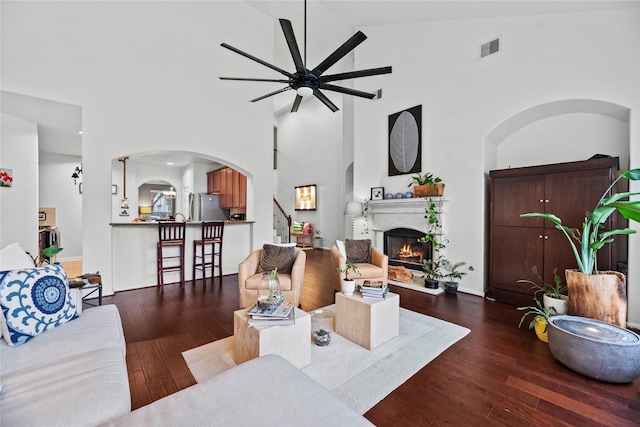 living room with dark hardwood / wood-style floors, ceiling fan, and high vaulted ceiling