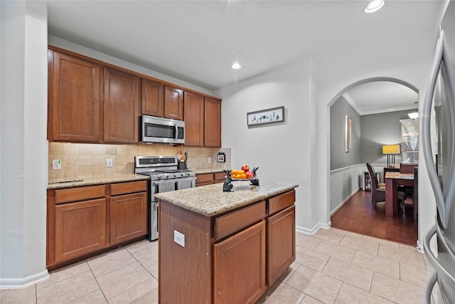 kitchen with a center island, light stone countertops, light tile patterned floors, and appliances with stainless steel finishes