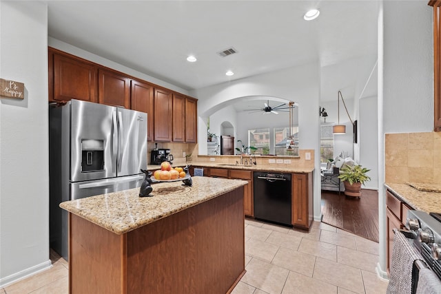 kitchen with sink, a center island, light stone countertops, and appliances with stainless steel finishes