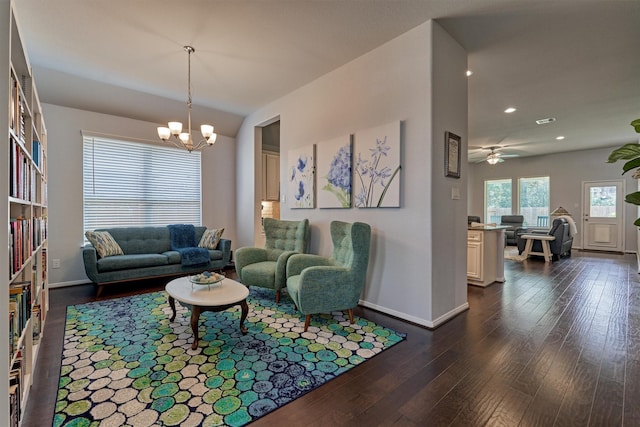 living room with ceiling fan with notable chandelier and dark hardwood / wood-style flooring