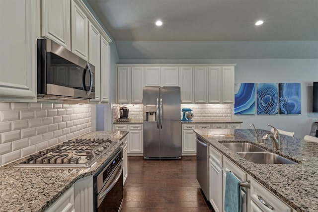 kitchen with sink, tasteful backsplash, light stone counters, white cabinets, and appliances with stainless steel finishes