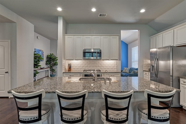 kitchen featuring decorative backsplash, appliances with stainless steel finishes, sink, white cabinets, and an island with sink