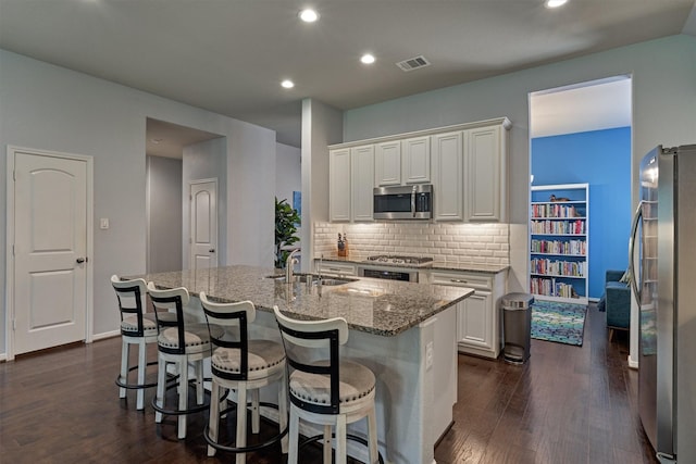 kitchen featuring stainless steel appliances, white cabinetry, a kitchen island with sink, and sink