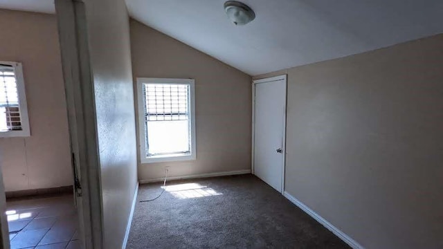 empty room with dark carpet and vaulted ceiling