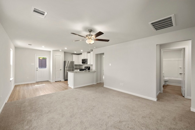 unfurnished living room featuring ceiling fan and light carpet