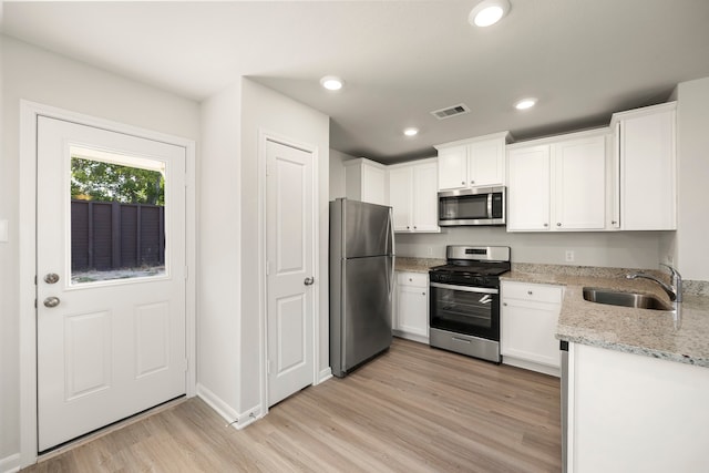 kitchen with white cabinetry, sink, stainless steel appliances, light stone counters, and light hardwood / wood-style flooring