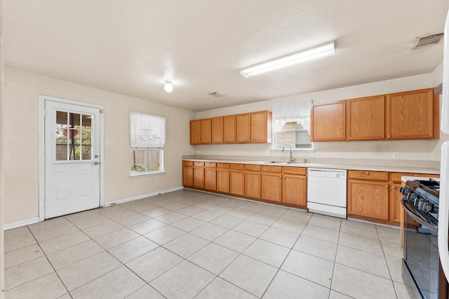 kitchen with light tile patterned floors, white dishwasher, black range, and sink