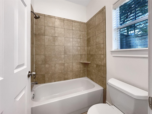 bathroom with tiled shower / bath combo and toilet