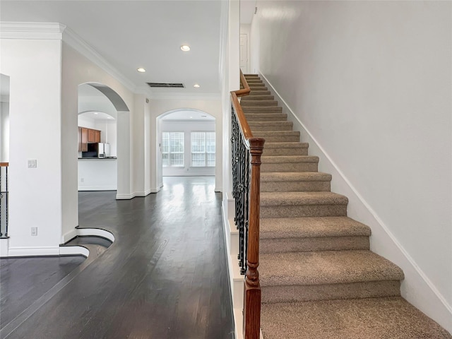 staircase featuring wood-type flooring and crown molding