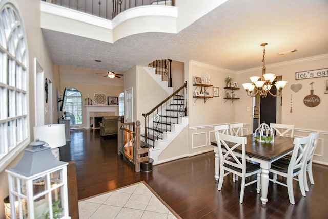 tiled dining space featuring ceiling fan with notable chandelier and crown molding