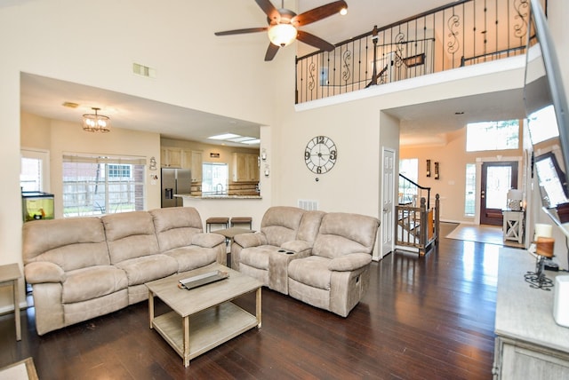 living room with a towering ceiling, a wealth of natural light, and dark wood-type flooring