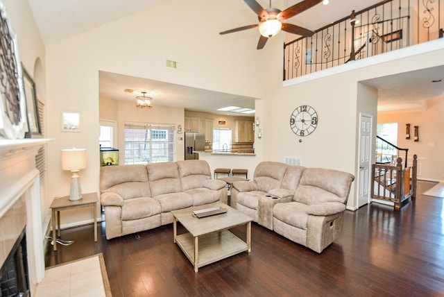 living room with a fireplace, ceiling fan with notable chandelier, dark hardwood / wood-style floors, and high vaulted ceiling