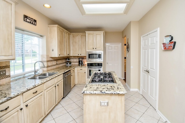 kitchen with light stone countertops, light brown cabinetry, stainless steel appliances, sink, and a kitchen island