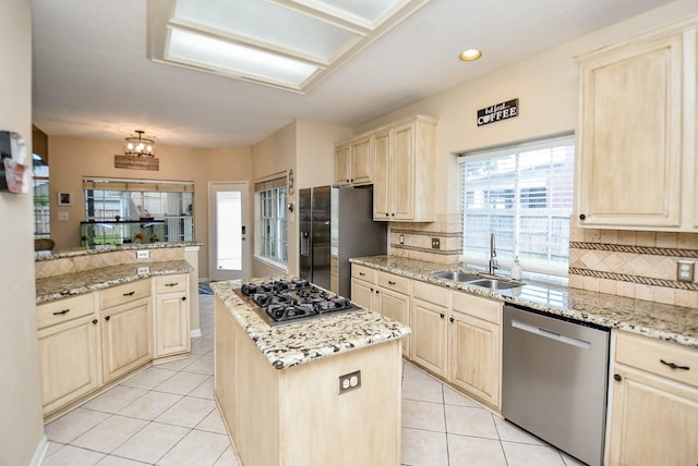 kitchen featuring appliances with stainless steel finishes, light stone counters, a kitchen island, and sink