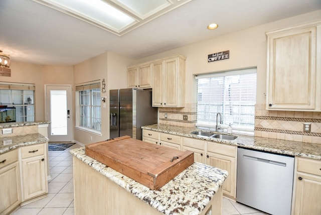 kitchen with light stone countertops, stainless steel appliances, a kitchen island, and sink