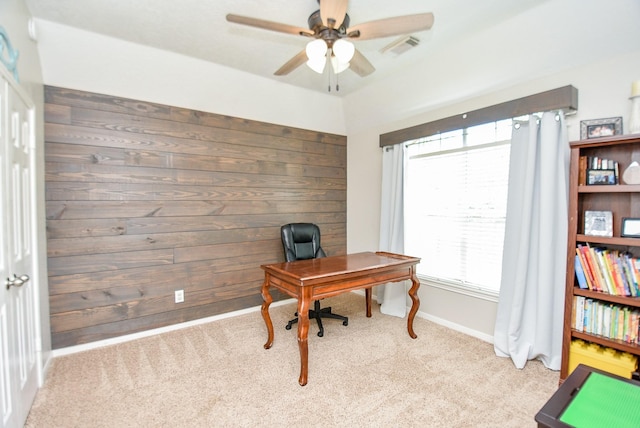 office area featuring light carpet, ceiling fan, and wood walls