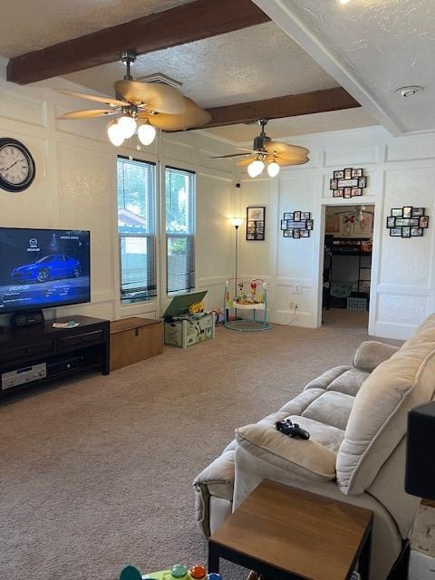 carpeted living room featuring ceiling fan, beam ceiling, and a textured ceiling