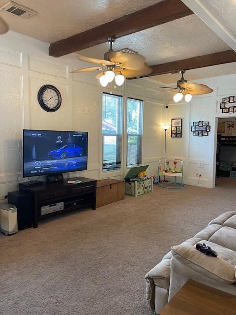 living room with carpet, ceiling fan, beam ceiling, and a textured ceiling