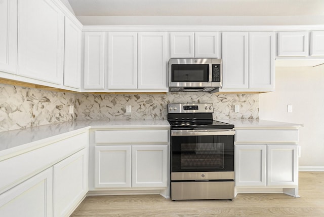 kitchen featuring white cabinets, light wood-type flooring, appliances with stainless steel finishes, and tasteful backsplash