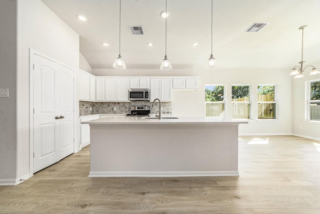 kitchen featuring white cabinetry, sink, stainless steel appliances, tasteful backsplash, and a kitchen island with sink