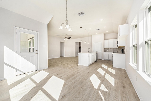 unfurnished living room featuring ceiling fan with notable chandelier, light hardwood / wood-style flooring, vaulted ceiling, and sink