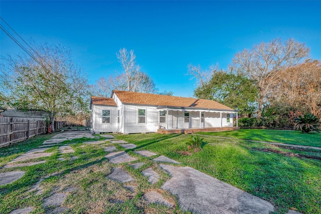 rear view of property with covered porch and a yard