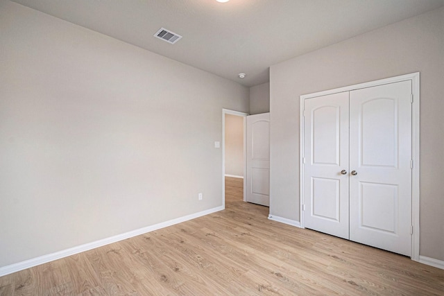 unfurnished bedroom with a closet and light wood-type flooring