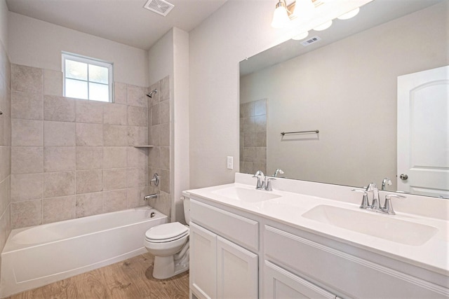 full bathroom featuring vanity, hardwood / wood-style flooring, toilet, and tiled shower / bath