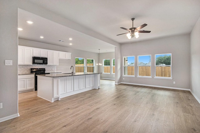 kitchen featuring range with electric cooktop, an island with sink, decorative backsplash, white cabinets, and light wood-type flooring