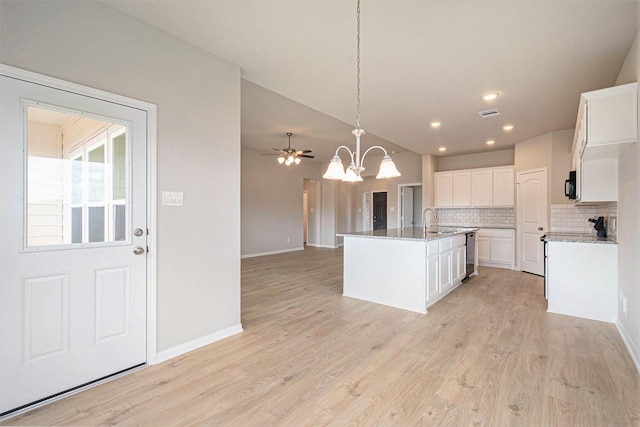 kitchen featuring decorative backsplash, a kitchen island with sink, light hardwood / wood-style flooring, white cabinets, and hanging light fixtures