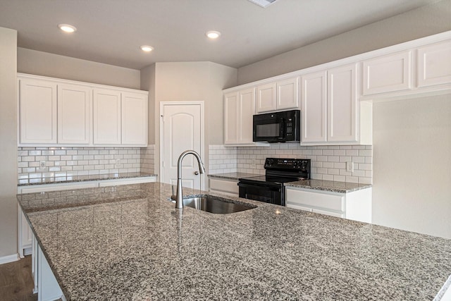 kitchen with white cabinetry, sink, an island with sink, dark stone counters, and black appliances