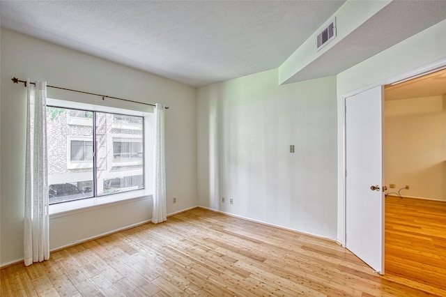 spare room with light hardwood / wood-style flooring and a textured ceiling