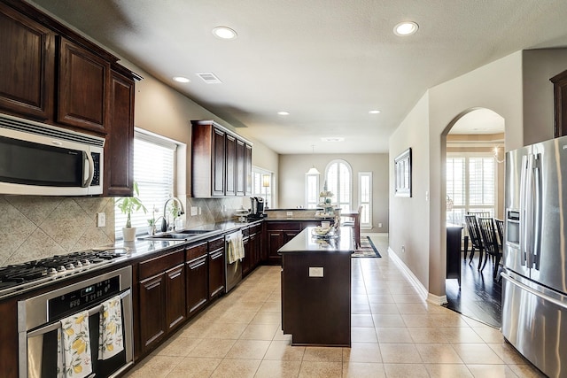 kitchen with decorative light fixtures, a kitchen island, plenty of natural light, and stainless steel appliances