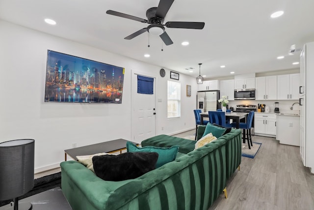 living room featuring ceiling fan, sink, and light hardwood / wood-style floors