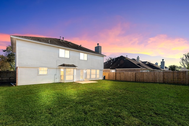 back house at dusk featuring a yard