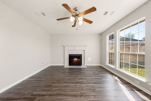 unfurnished living room featuring dark hardwood / wood-style floors, ceiling fan, and a tiled fireplace