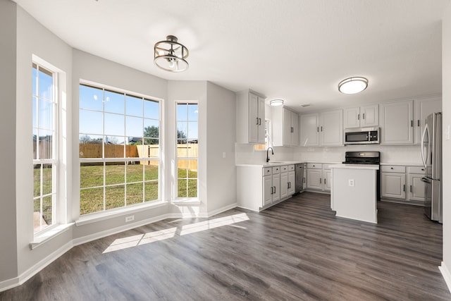 kitchen featuring stainless steel appliances, dark wood-type flooring, sink, a center island, and white cabinetry