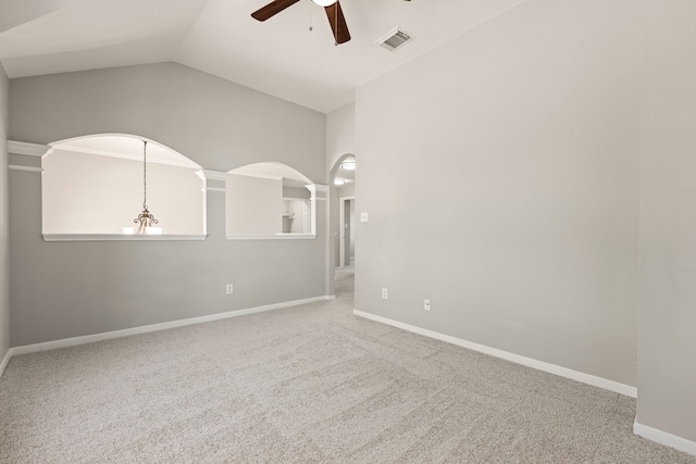 carpeted empty room featuring ceiling fan with notable chandelier and vaulted ceiling