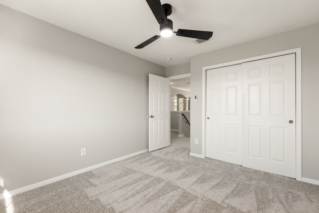 unfurnished bedroom featuring ceiling fan, a closet, and light colored carpet