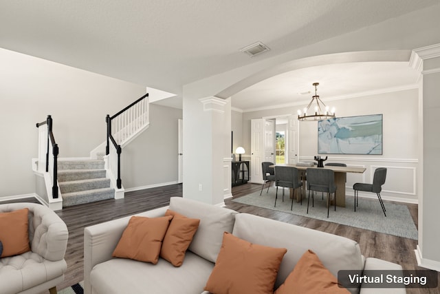 living room featuring dark hardwood / wood-style flooring, ornate columns, crown molding, and a chandelier