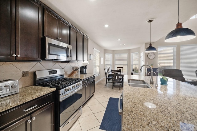 kitchen featuring light stone countertops, stainless steel appliances, tasteful backsplash, and sink