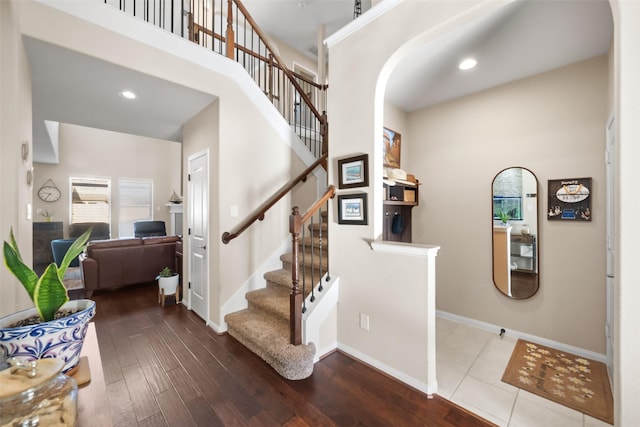 stairs featuring hardwood / wood-style floors and a high ceiling