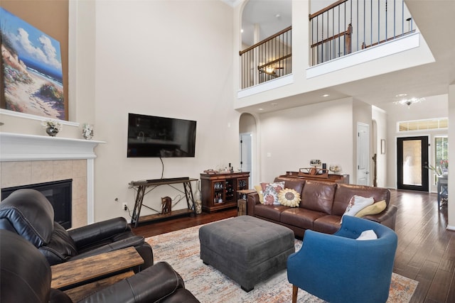 living room with dark hardwood / wood-style floors, a towering ceiling, french doors, and a tiled fireplace