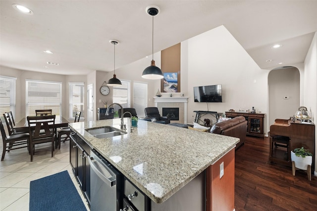 kitchen with pendant lighting, sink, an island with sink, and a tiled fireplace