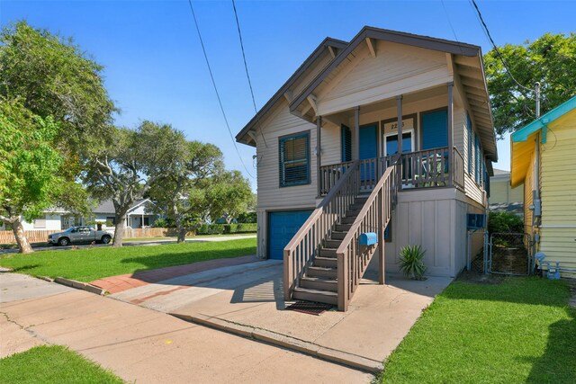 view of front of house featuring covered porch, a front yard, and a garage