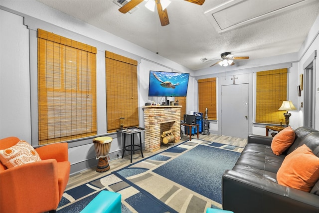 living area featuring a textured ceiling, a fireplace, wood finished floors, and a ceiling fan