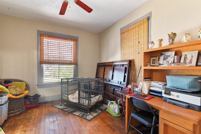 home office with a textured ceiling, ceiling fan, and dark hardwood / wood-style floors