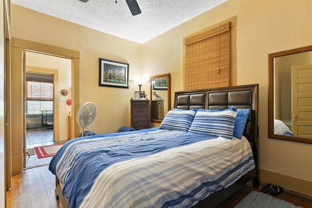 bedroom with a textured ceiling, ceiling fan, wood finished floors, and baseboards