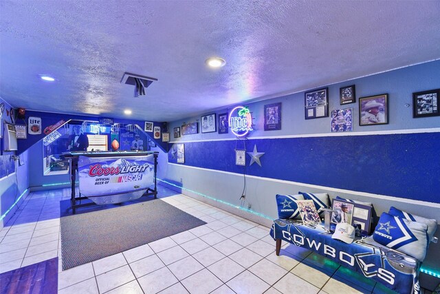 game room with tile patterned flooring and a textured ceiling