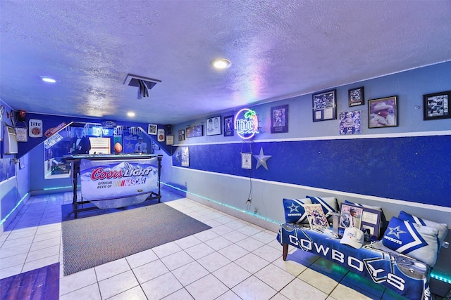 recreation room featuring tile patterned flooring and a textured ceiling